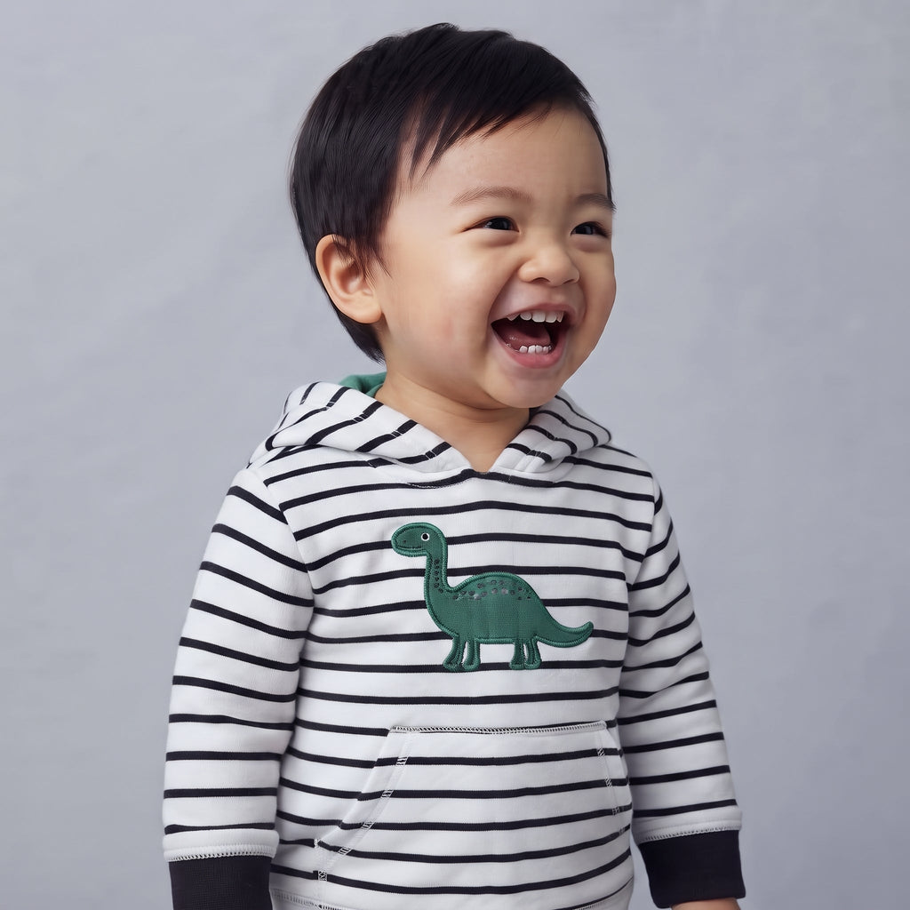 Bebé riendo feliz con buzo EmpiBy de rayas blancas y negras con estampado de dinosaurio verde en el pecho