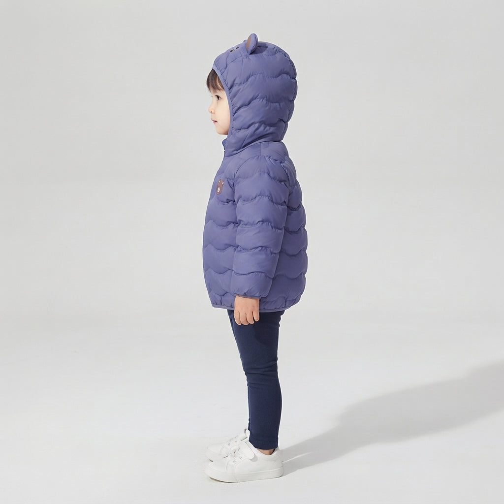 Niño de perfil vistiendo chaqueta acolchada EmpiBy color azul con capucha y orejas de osito, estilo casual infantil.