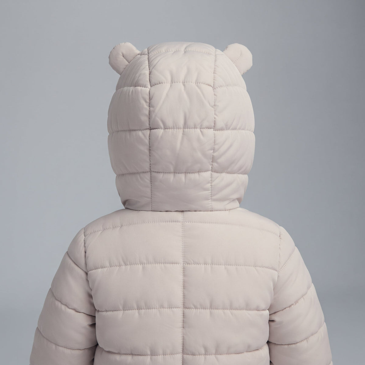 Vista trasera de la chaqueta acolchada EmpiBy Little Bear en color beige con capucha y orejitas de oso para bebé