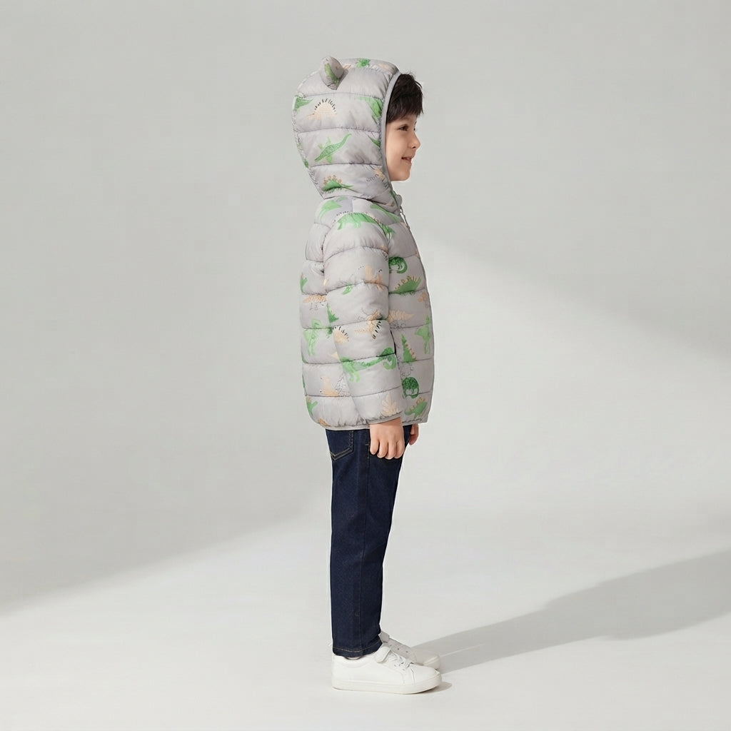Niño de perfil vistiendo chaqueta acolchada gris EmpiBy con estampado de dinosaurios y capucha con orejas