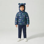 Niño vistiendo chaqueta acolchada azul EmpiBy con estampado de dinosaurios Mundo Jurásico y capucha con orejas