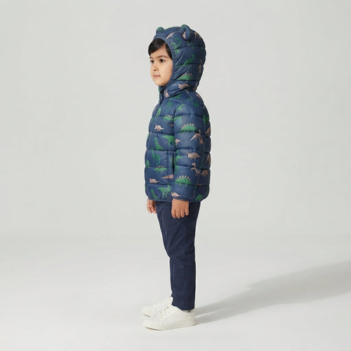 Niño vistiendo chaqueta acolchada EmpiBy azul con estampado de dinosaurios y capucha con orejas de dinosaurio