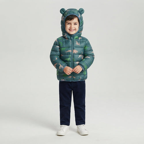 Niño sonriente vistiendo chaqueta acolchada EmpiBy verde bosque con estampado de dinosaurios y capucha con orejas