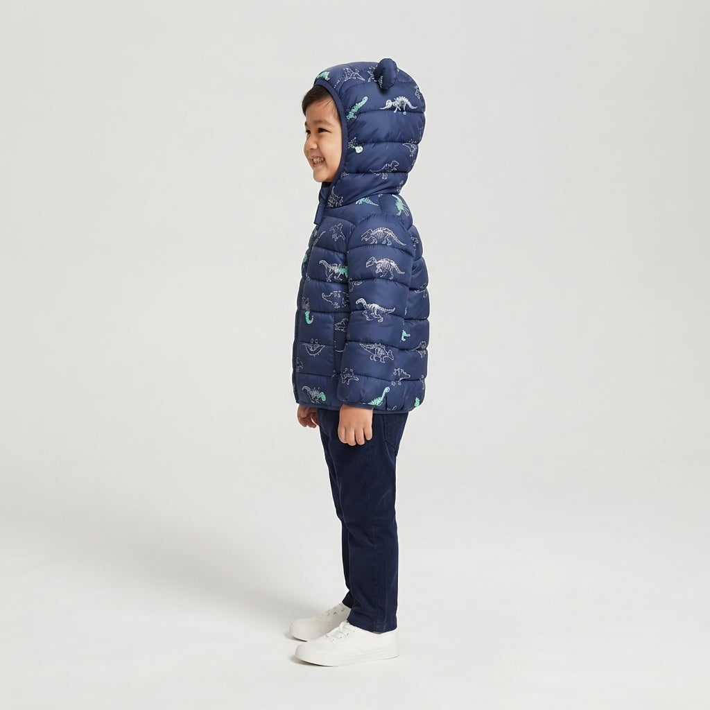 Niño sonriente vistiendo chaqueta acolchada EmpiBy azul marino con estampado de esqueletos de dinosaurios y capucha
