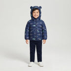 Niño sonriente vistiendo chaqueta acolchada azul marino EmpiBy con estampado de esqueletos de dinosaurios y capucha