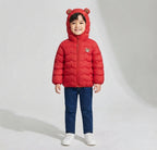 Niño vistiendo chaqueta acolchada impermeable roja de EmpiBy con capucha y orejas de oso, ideal para días de lluvia.