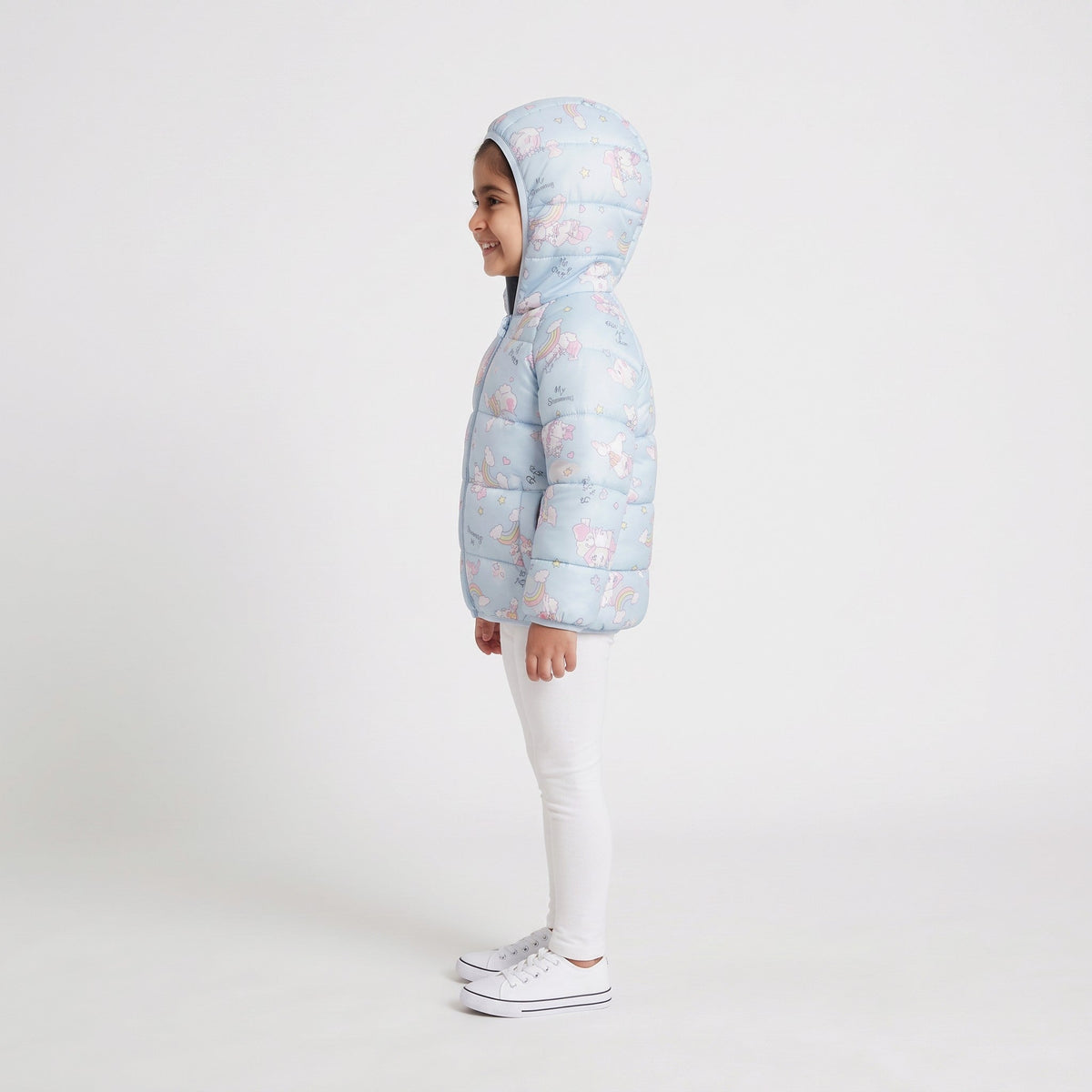 Niña vistiendo chaqueta acolchada EmpiBy con estampado de unicornios y arcoíris en tonos pastel con capucha