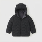 Chaqueta acolchada negra EmpiBy para niño con capucha y orejitas decorativas, diseño minimalista y cálido.