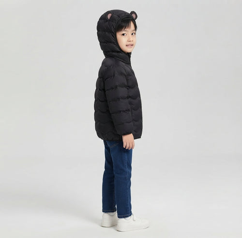 Niño vistiendo chaqueta acolchada negra con capucha y orejitas de EmpiBy sobre fondo gris claro