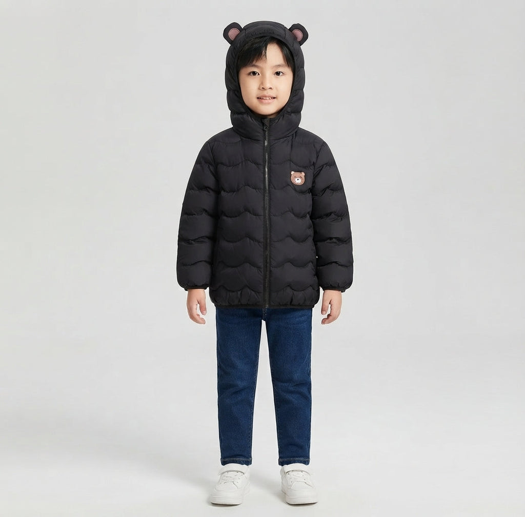 Niño vistiendo chaqueta acolchada negra EmpiBy con capucha y orejas de oso, diseño minimalista y cálido