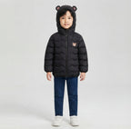 Niño vistiendo chaqueta acolchada negra EmpiBy con capucha y orejas de oso, diseño minimalista y cálido
