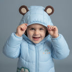 Niño sonriente con chaqueta acolchada azul EmpiBy con capucha de osito y orejitas decorativas