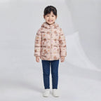 Niña vistiendo chaqueta acolchada EmpiBy beige claro con estampado de ositos y capucha, combinada con jeans azules.