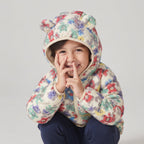 Niña sonriente con chaqueta acolchada EmpiBy con estampado de ositos y flores y capucha con orejitas