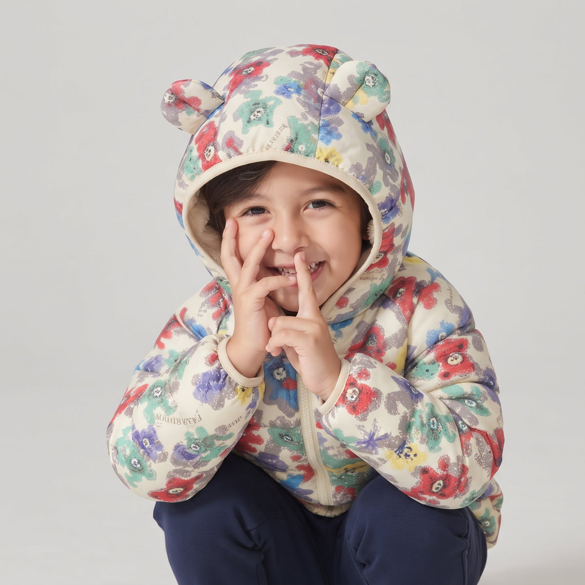 Niña sonriente con chaqueta acolchada EmpiBy con estampado de ositos y flores y capucha con orejitas