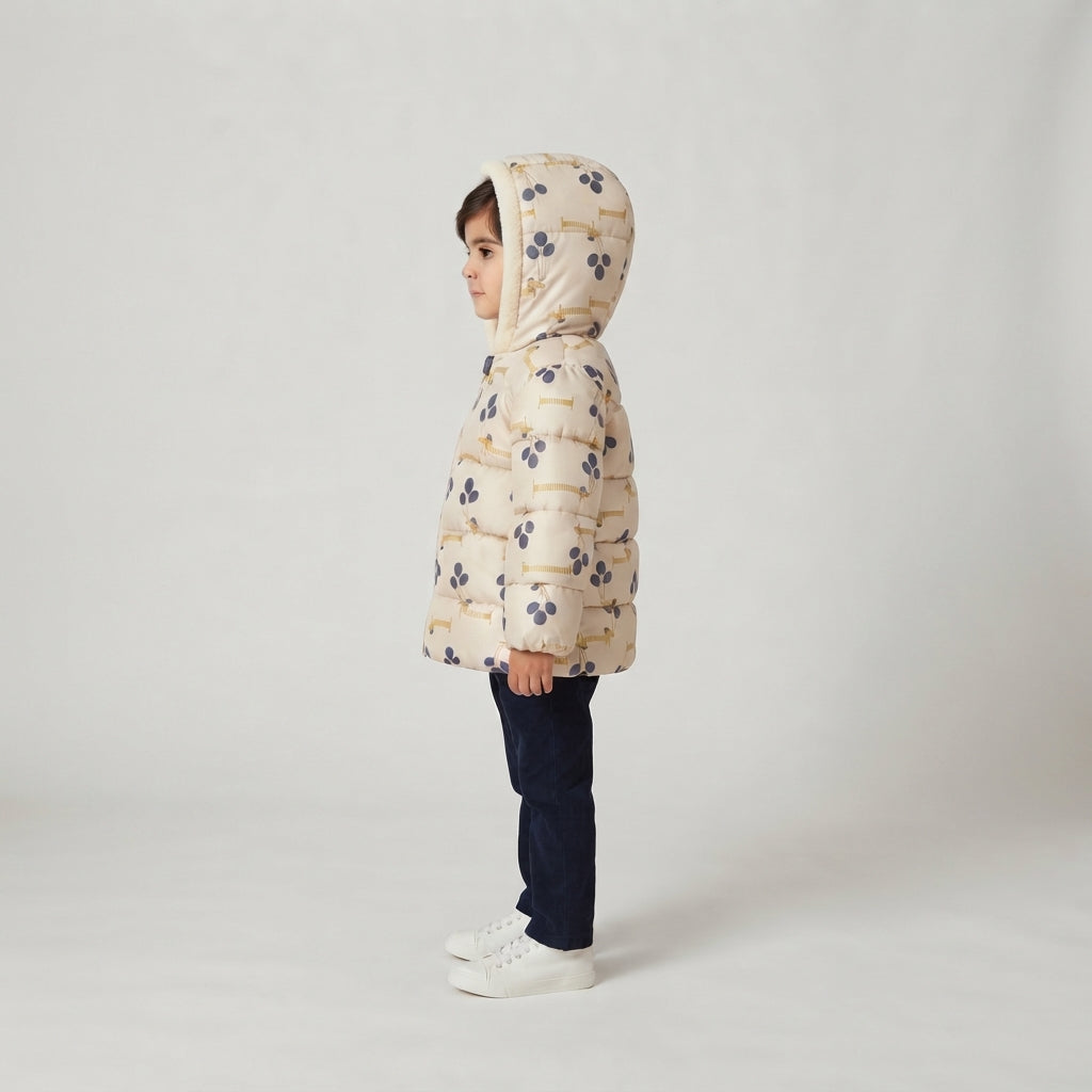 Niña vistiendo chaqueta acolchada EmpiBy con estampado de perritos, capucha y diseño abrigado en color crema