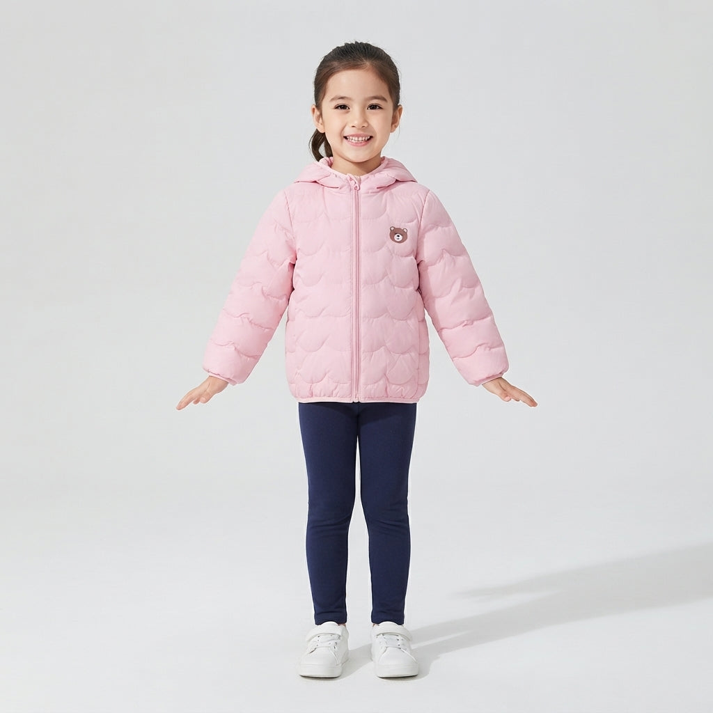 Niña sonriente vistiendo chaqueta acolchada rosa suave de EmpiBy con capucha y detalle de oso en el pecho