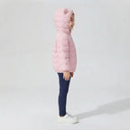 Niña vistiendo chaqueta acolchada rosa suave con capucha de orejitas de la marca EmpiBy sobre fondo neutro