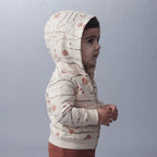 Bebé con chaqueta beige con capucha y estampado de cocodrilos de EmpiBy, vista lateral, estilo casual y cómodo.