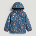 Chaqueta impermeable azul EmpiBy con estampado de dinosaurios coloridos, rayos y arcoíris, incluye capucha integrada.