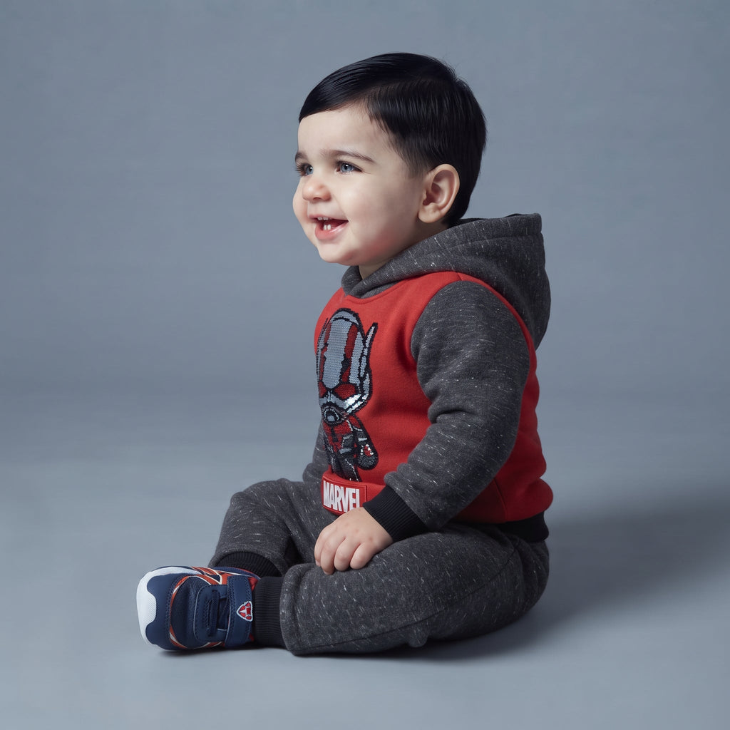 Bebé sonriente con conjunto EmpiBy de dos piezas de Ant-Man en gris melange y rojo con capucha y detalles brillantes.