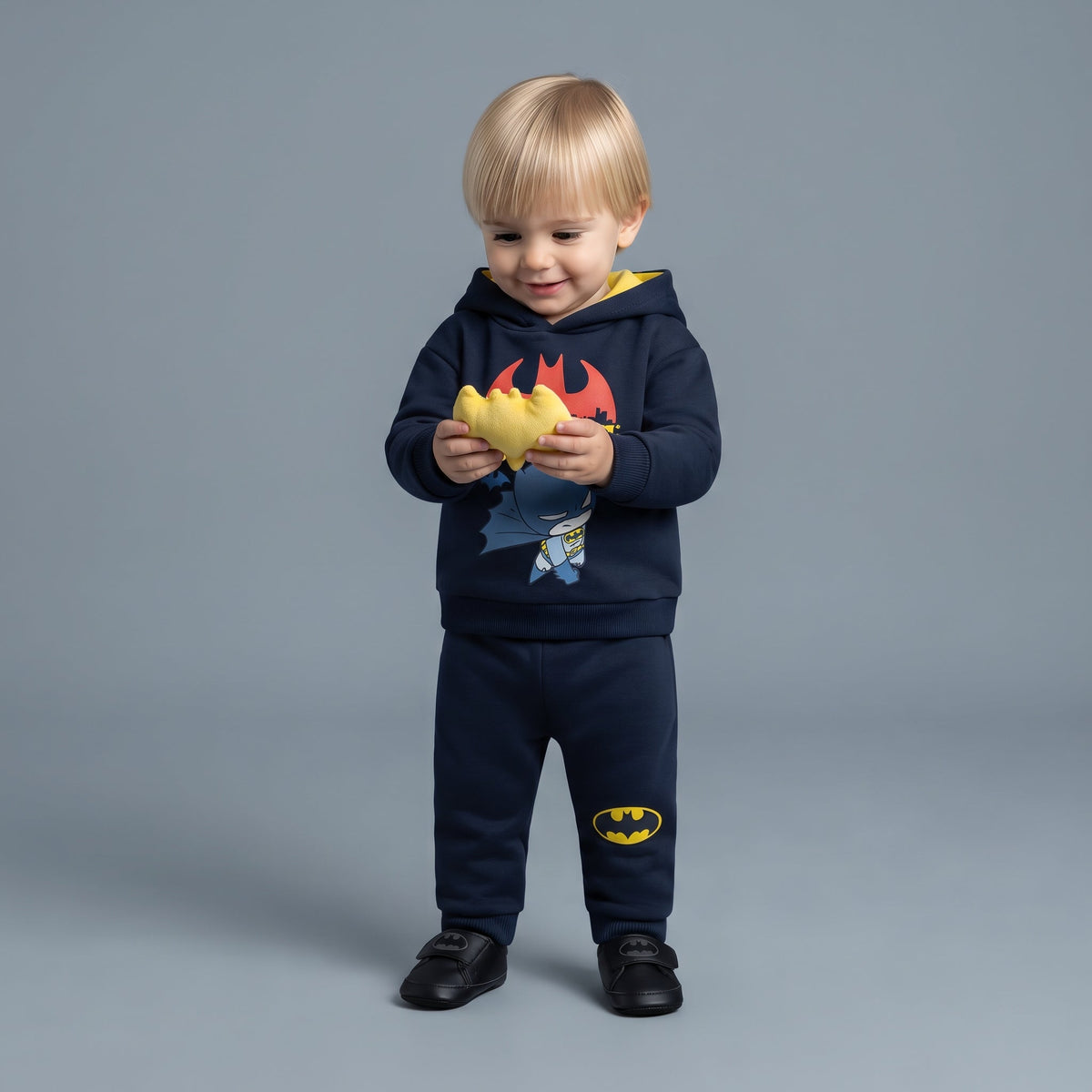 Niño pequeño con conjunto EmpiBy de Batman azul marino, sudadera con capucha amarilla y pantalón jogger cómodo.