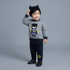 Niño pequeño vistiendo conjunto EmpiBy de Batman con sudadera gris, pantalón jogger azul marino y gorro con orejas.