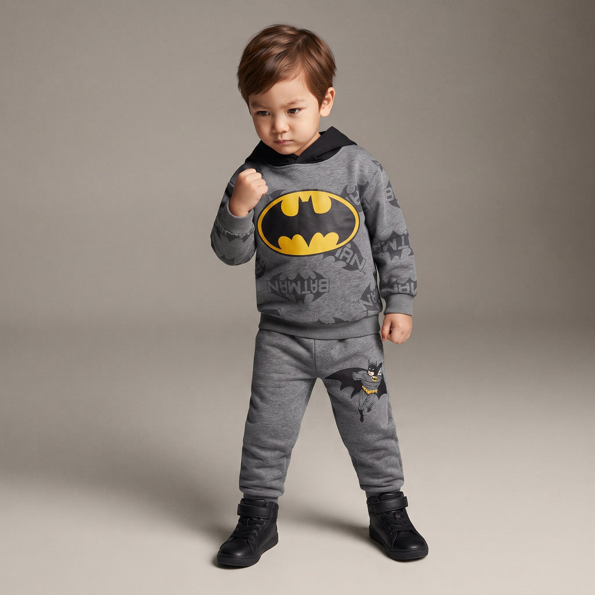 Niño vistiendo conjunto EmpiBy de dos piezas gris de Batman con sudadera de capucha y logo amarillo en el pecho