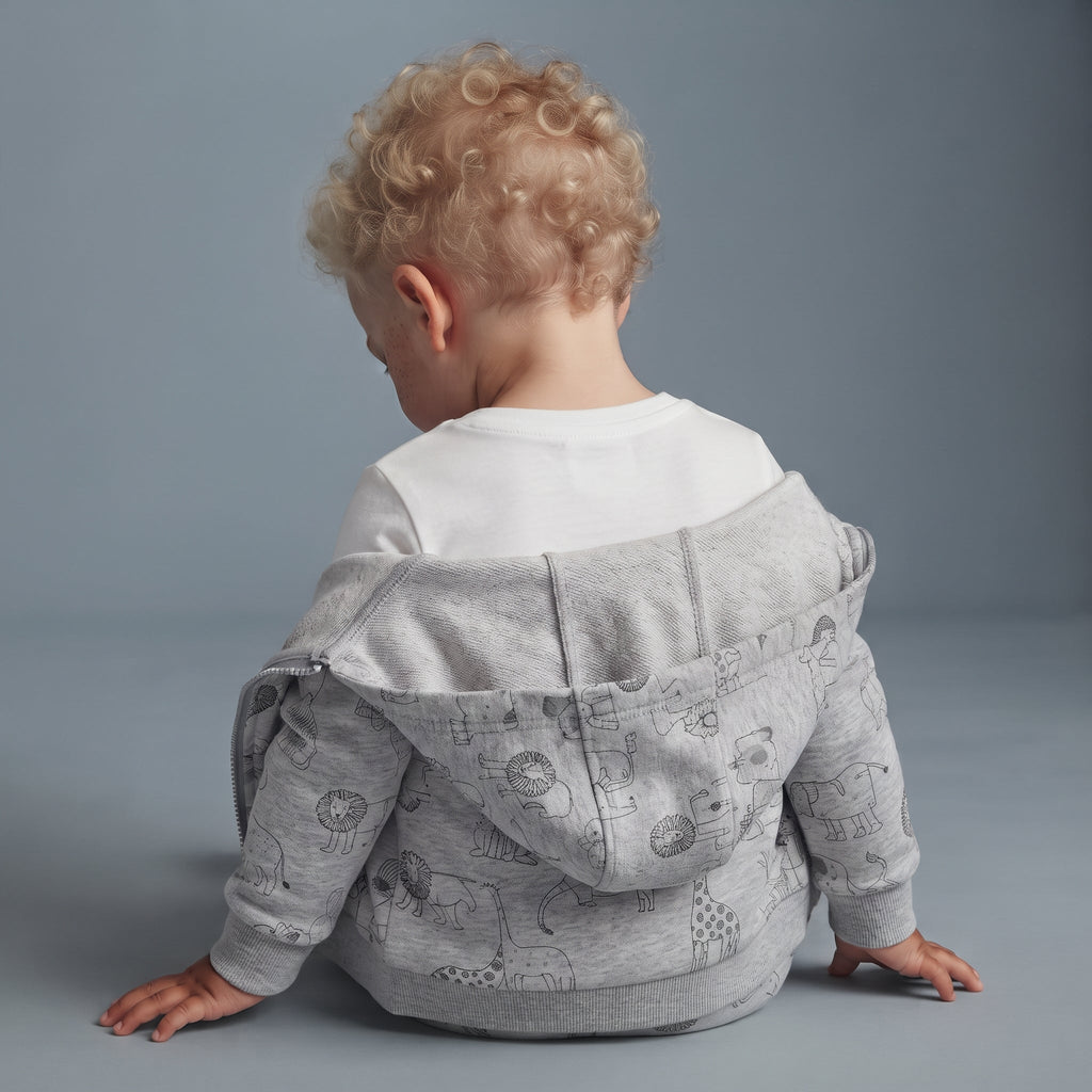Bebé con conjunto EmpiBy de 3 piezas: chaqueta gris con capucha y estampado de animales, sobre body blanco.