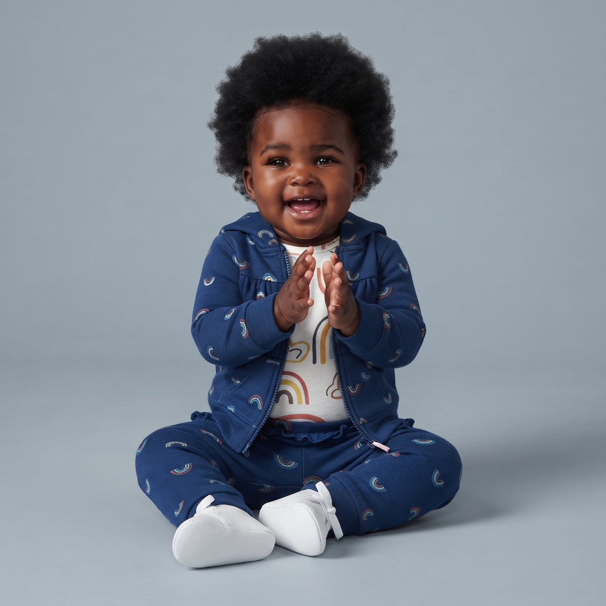 Bebé feliz con conjunto de 3 piezas EmpiBy azul oscuro con estampado de arcoíris, chaqueta, body y pantalón.