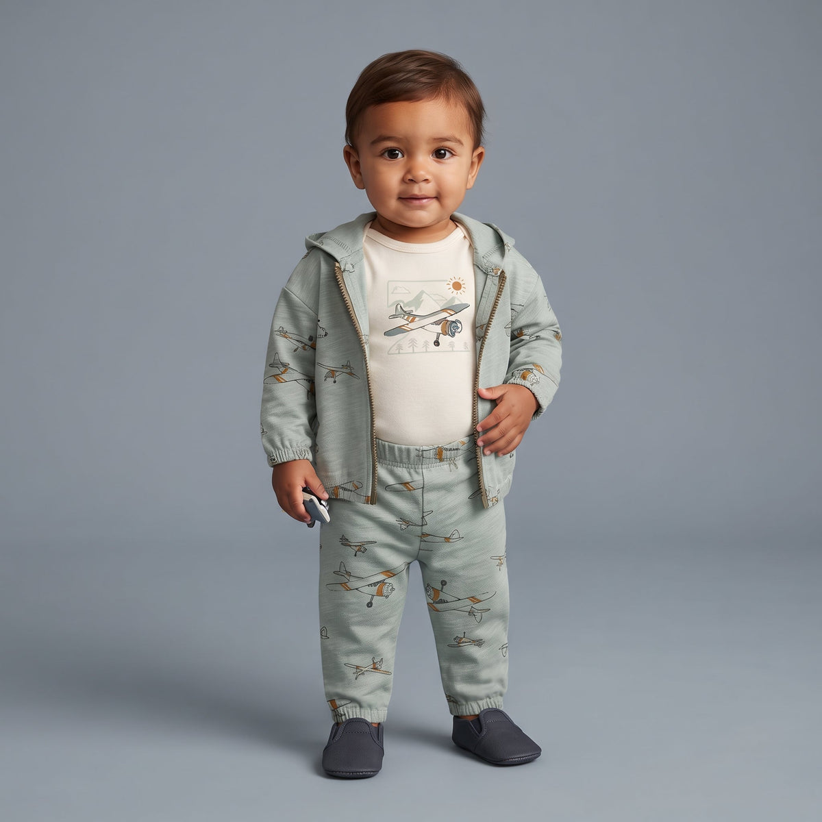 Bebé niño vistiendo conjunto EmpiBy de 3 piezas verde salvia con estampado de aviones y body beige con diseño