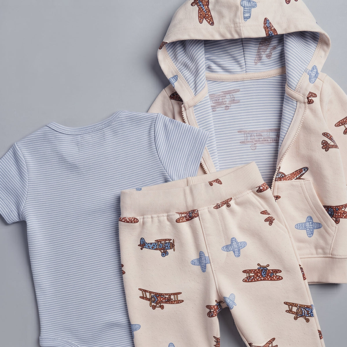 Conjunto EmpiBy de 3 piezas para bebé: body a rayas, chaqueta con capucha y pantalón con estampado de avionetas.