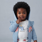 Bebé con conjunto EmpiBy de 3 piezas: chaqueta azul con capucha, body blanco con estampado de unicornio y pantalón