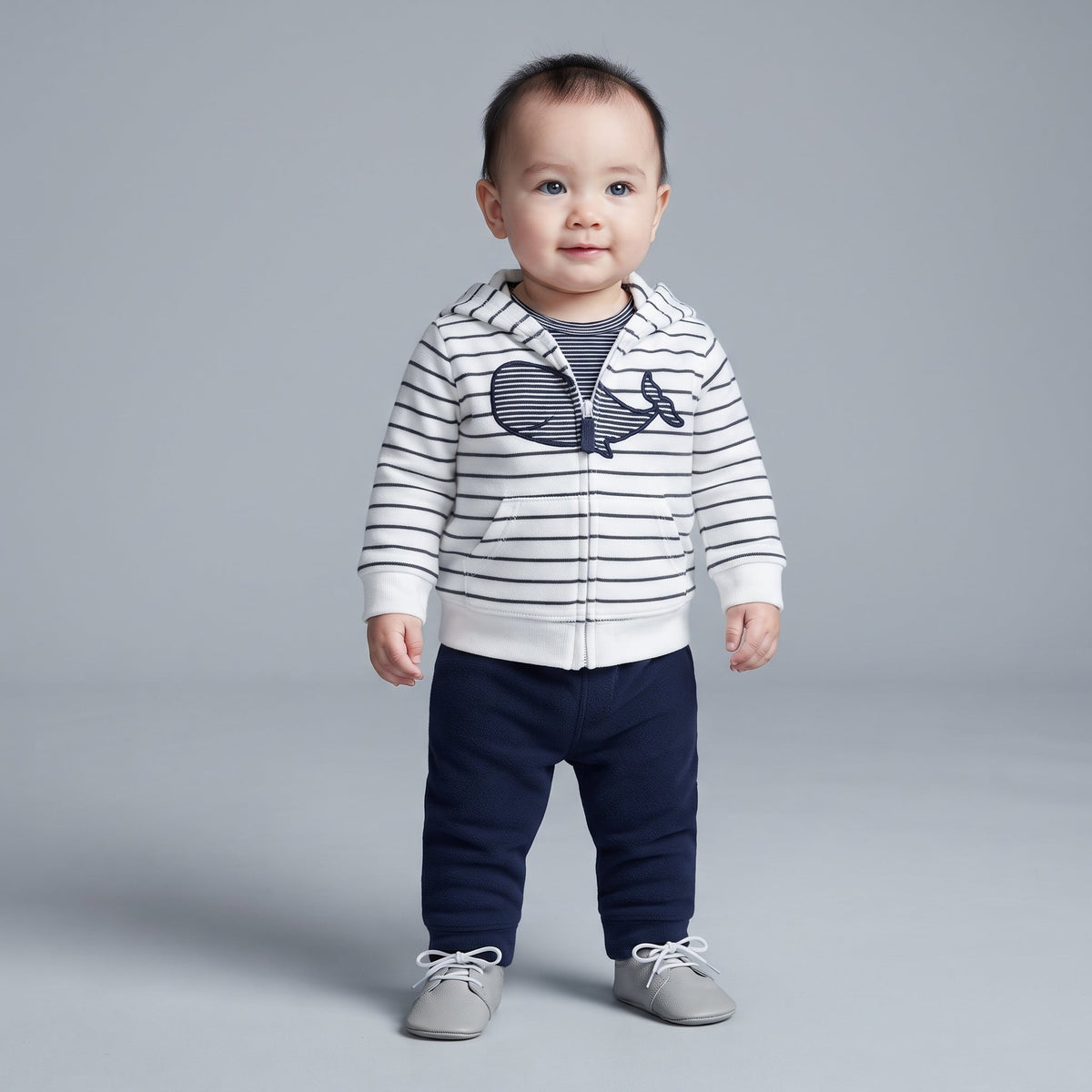Bebé niño vistiendo conjunto EmpiBy de 3 piezas: chaqueta a rayas con ballena, body y pantalón azul marino.