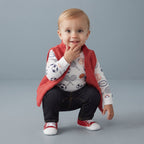Bebé sonriente con conjunto EmpiBy de 3 piezas: chaleco rojo acolchado, body estampado y pantalón oscuro de mezclilla.
