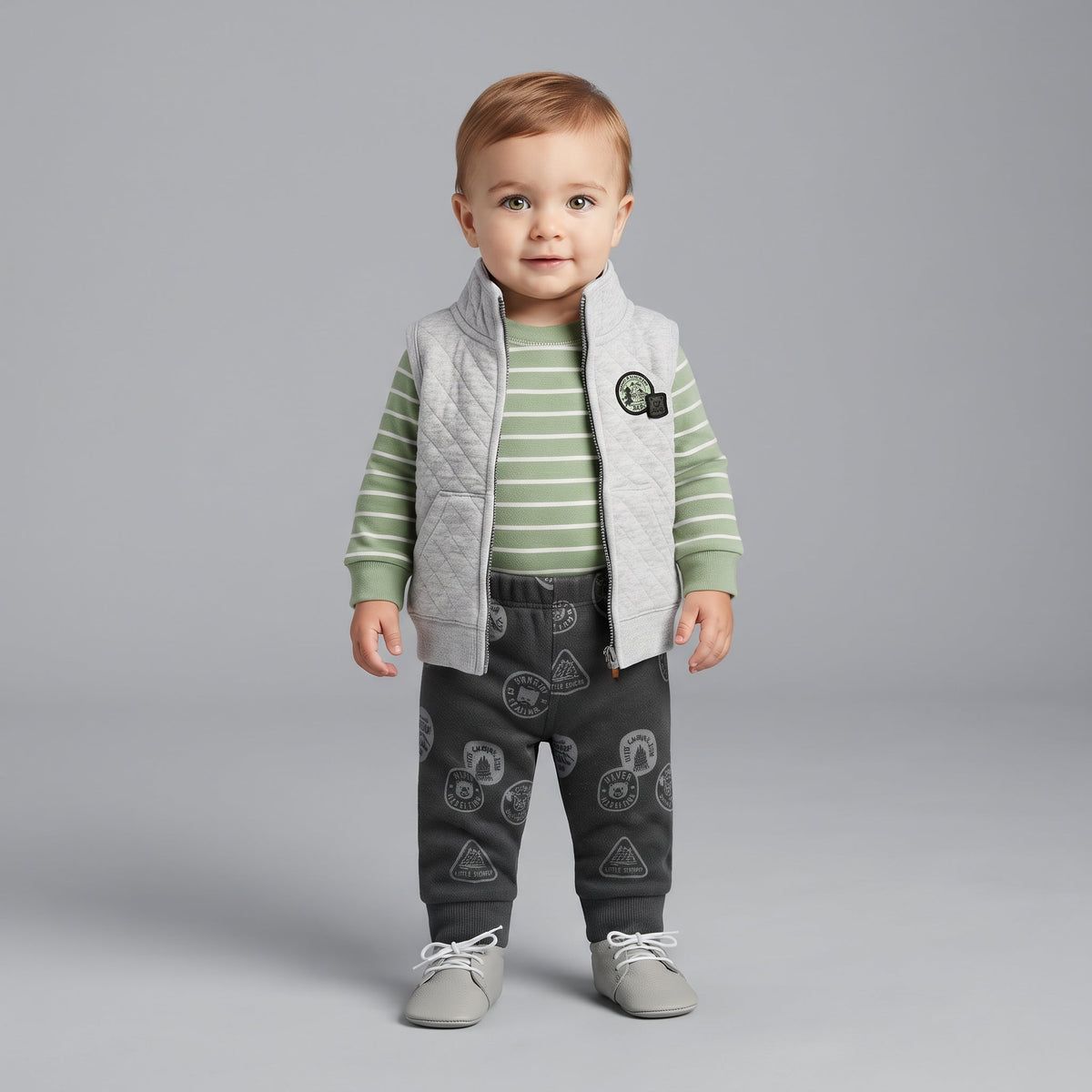 Conjunto de 3 piezas EmpiBy para bebé niño con chaleco acolchado gris, body a rayas verde y pantalón estampado.