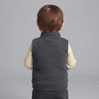 Vista trasera de bebé niño con conjunto EmpiBy de chaleco acolchado gris oscuro y body de rayas amarillas