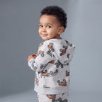 Bebé niño vistiendo chaqueta con capucha gris EmpiBy con estampado de cuatrimotos naranjas y verdes
