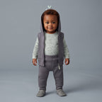 Bebé con conjunto EmpiBy de 3 piezas: chaleco gris con capucha de dinosaurio, body verde con dinosaurios y pantalón.