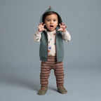 Bebé con conjunto EmpiBy de 3 piezas: chaleco verde con capucha de dinosaurio, body estampado y pantalón a rayas.