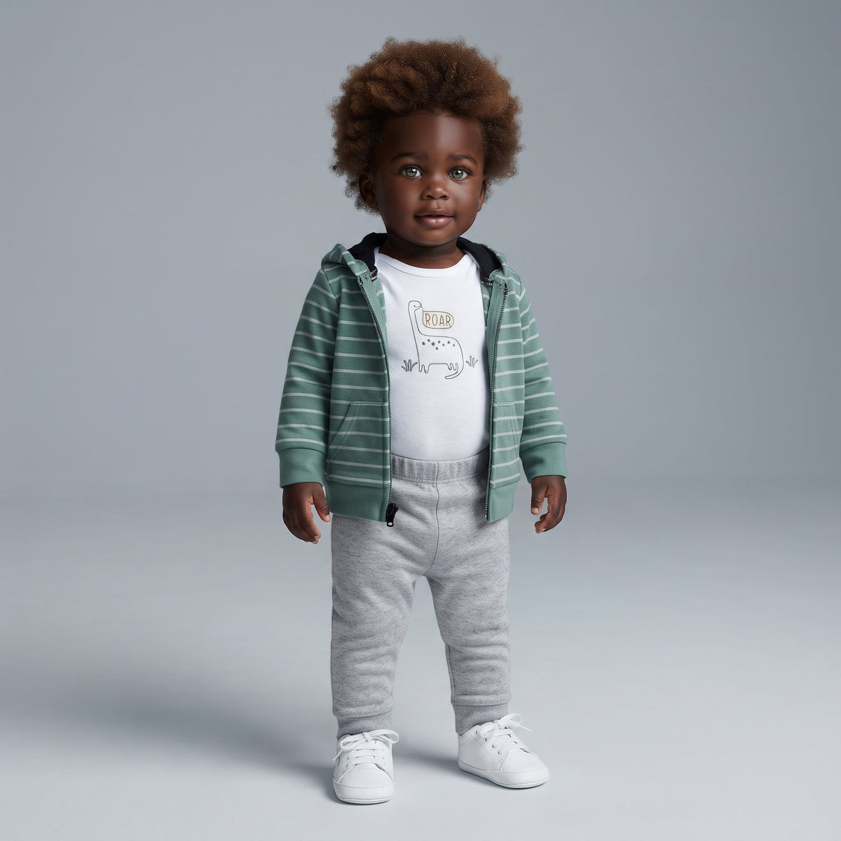 Bebé con conjunto EmpiBy de 3 piezas: chaqueta de rayas verde con cresta, body blanco con dinosaurio y pantalón gris.