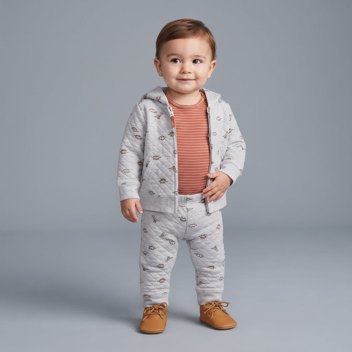 Bebé niño vistiendo conjunto EmpiBy de 3 piezas gris con estampado de dinosaurios, body terracota y chaqueta acolchada