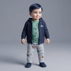 Bebé con conjunto de 3 piezas EmpiBy: chaqueta azul, body verde oliva con dinosaurios y pantalón gris estampado.