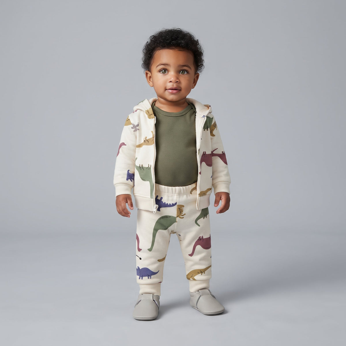 Bebé con conjunto EmpiBy de 3 piezas: chaqueta y pantalón beige con dinosaurios y body verde oliva de manga larga.