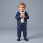 Niño pequeño con conjunto EmpiBy de tres piezas azul oscuro, chaqueta con cresta de dinosaurio y body estampado.