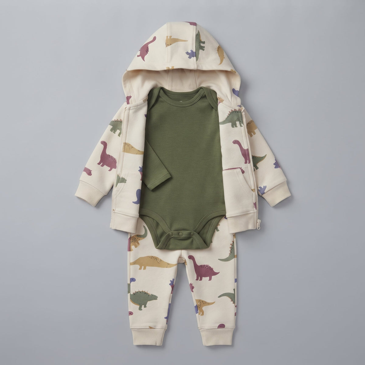 Conjunto EmpiBy de 3 piezas para bebé con estampado de dinosaurios, chaqueta con capucha, body verde y pantalón beige.