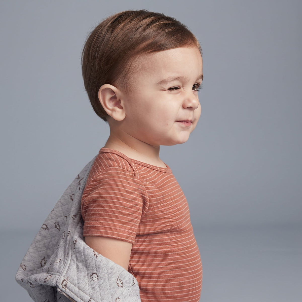 Niño pequeño con conjunto EmpiBy de body terracota a rayas y chaqueta acolchada gris con estampado de dinosaurios