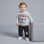 Bebé con conjunto EmpiBy de dos piezas: sudadera gris con estampado Disney y pantalón jogger negro cómodo.