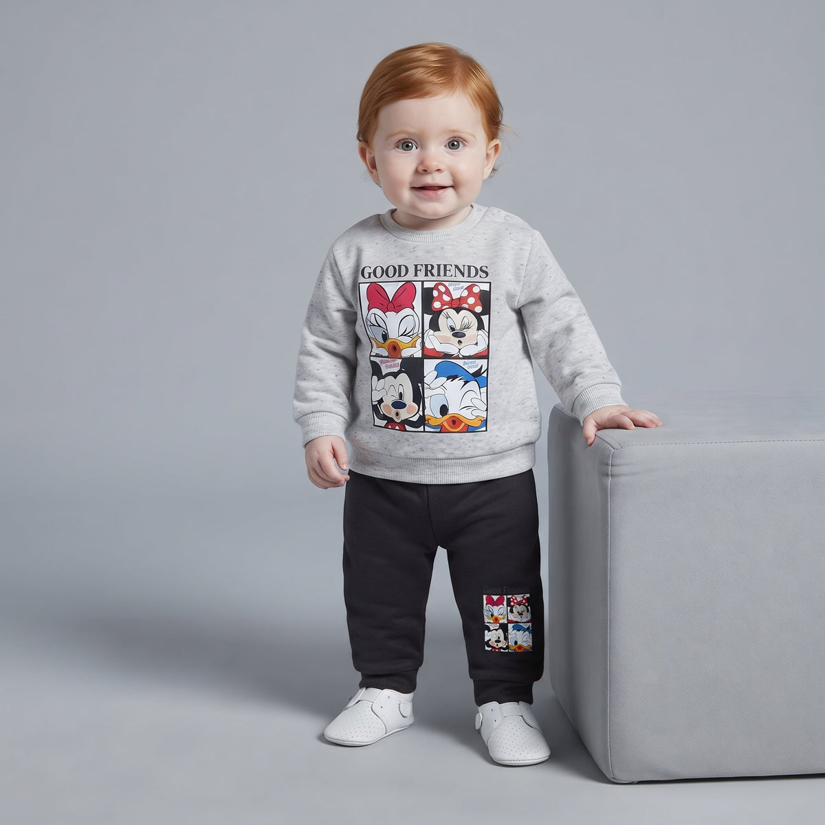 Bebé con conjunto EmpiBy de dos piezas: sudadera gris con estampado Disney y pantalón jogger negro cómodo.