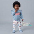 Bebé niña vistiendo conjunto EmpiBy de 3 piezas: chaqueta azul con volantes, body blanco y pantalón de dinosaurios.